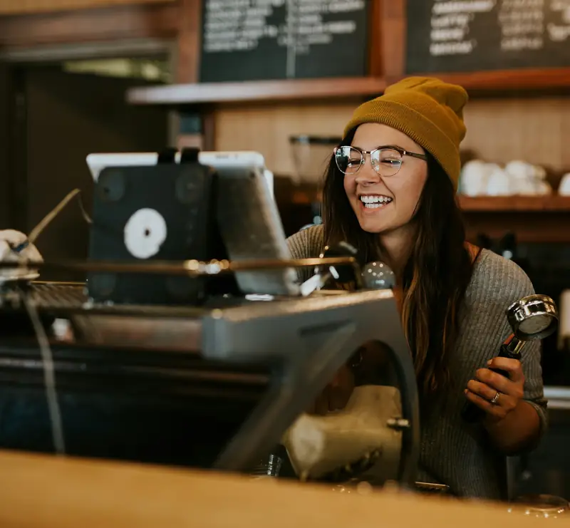 Smiling barista preparing espresso behind a coffee bar