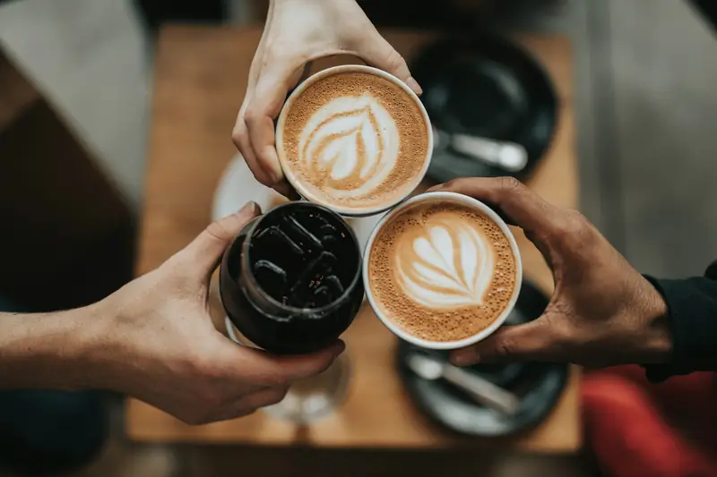Two people raising cups of latte together