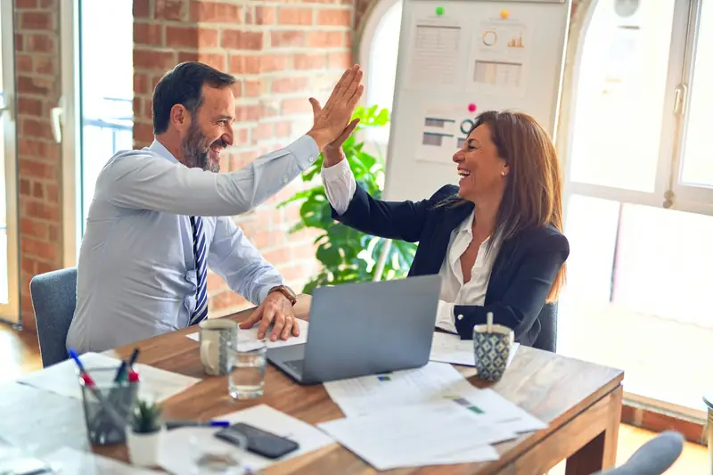Two business partners celebrating an agreement at a meeting table