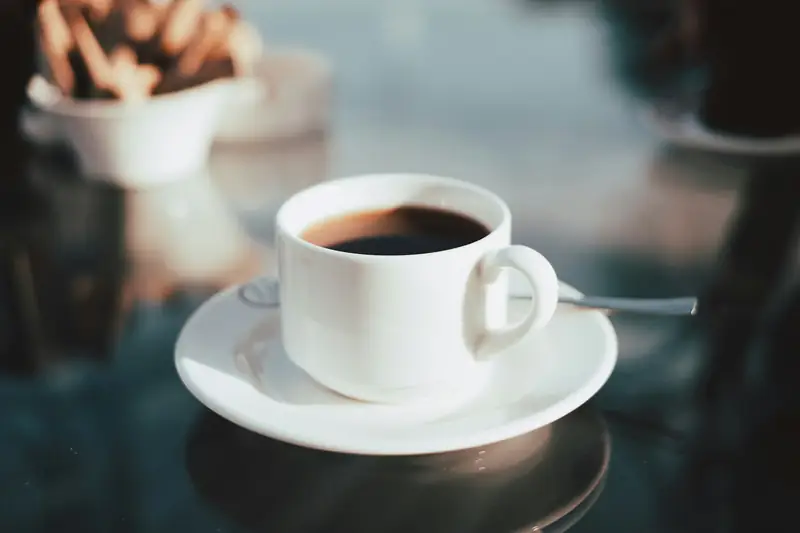 White cup of black coffee on a saucer